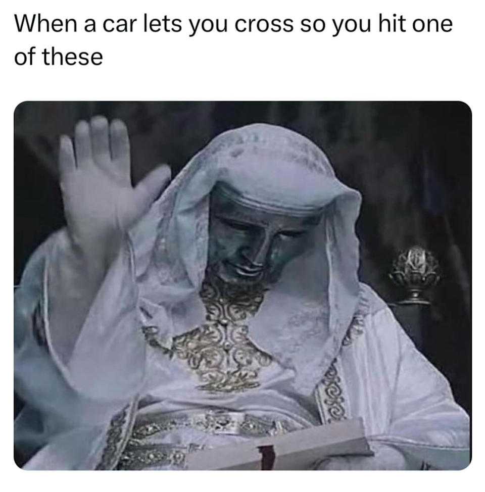 A humorous image of a statue raising one hand, resembling stopping traffic. The caption relates to crossing the street