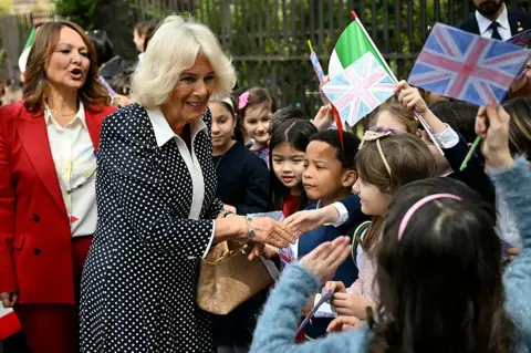Getty Images The Queen shakes hands with a group of young students who are waving flags of the United Kingdom
