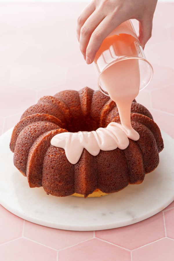 Drizzling the pale pink glaze over the top of the cooled bundt cake.