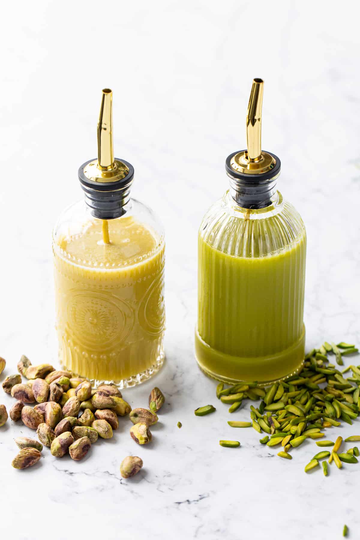 Side by side comparison of two bottles of Homemade Pistachio Syrup made with different kinds of pistachios (one is clearly greener than the other).