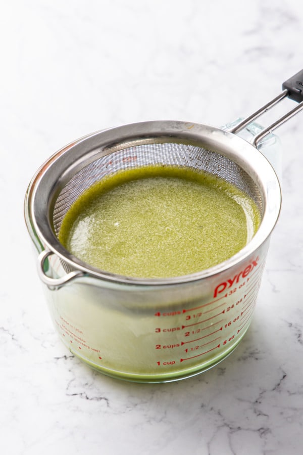 Sieve sitting on top of a glass measuring cup, allowing the syrup to drip through at its own pace.