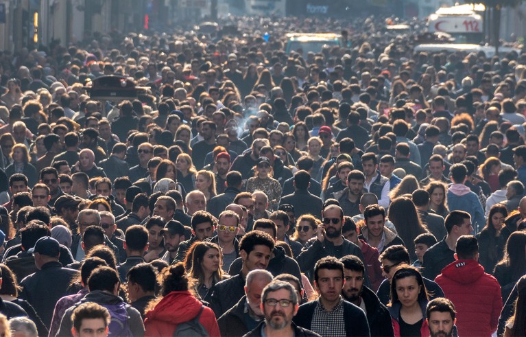Huge crowd walking filling a large street.