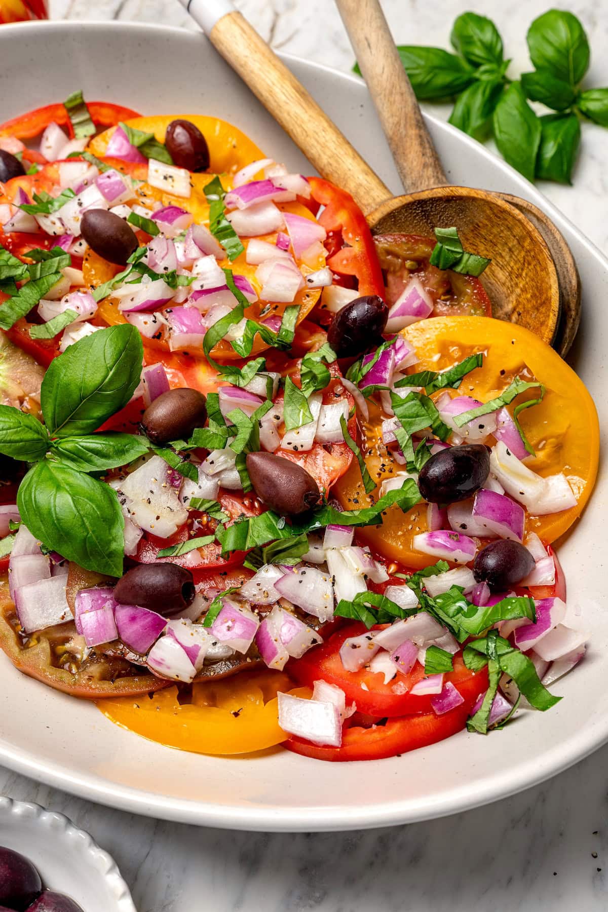 Heirloom tomato salad on platter with olives and onions