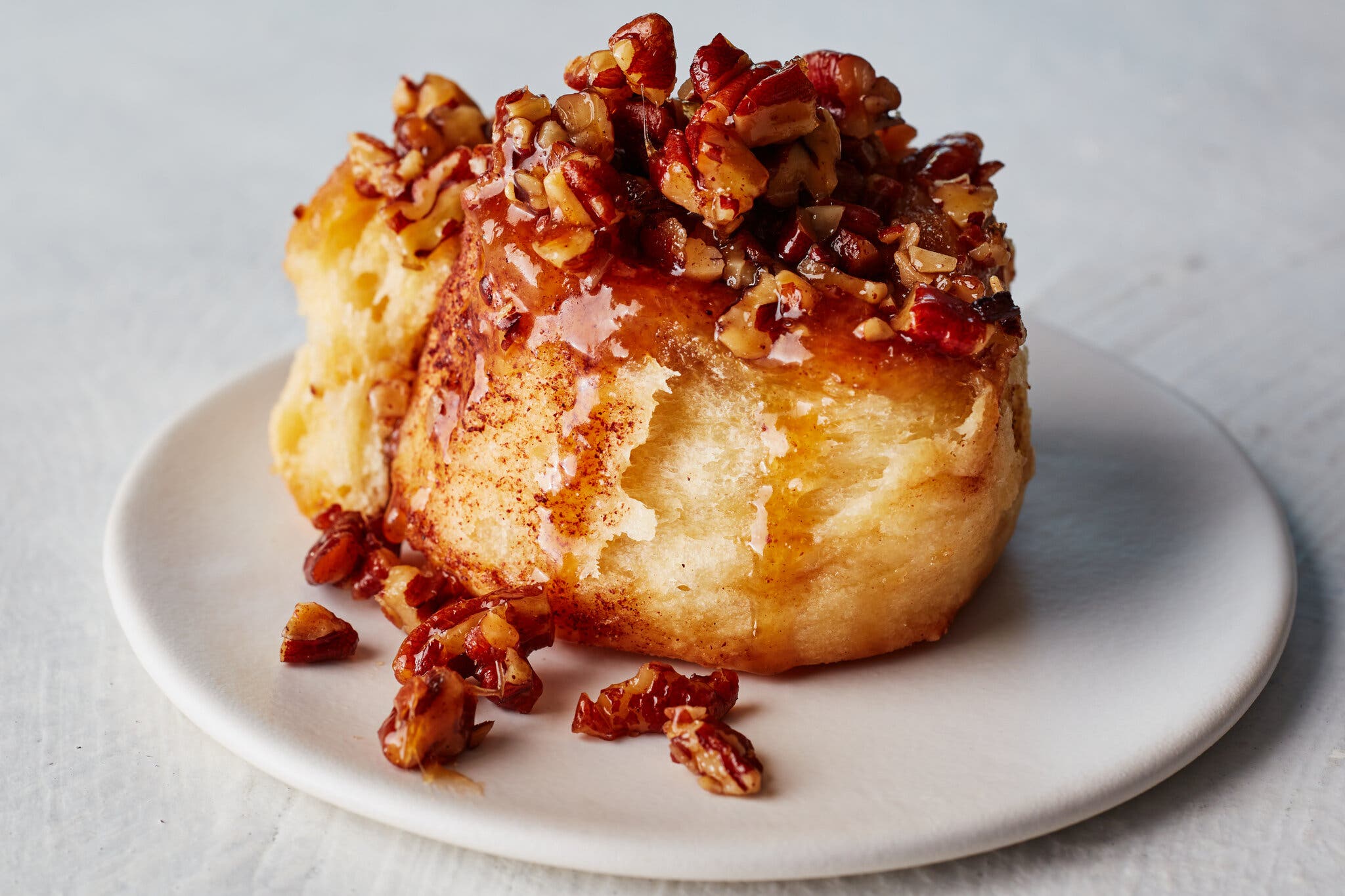 A side image of a sticky bun topped with pecans.