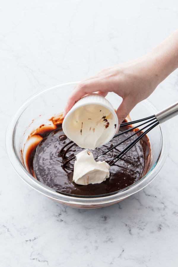 Adding sour cream to melted chocolate frosting base.