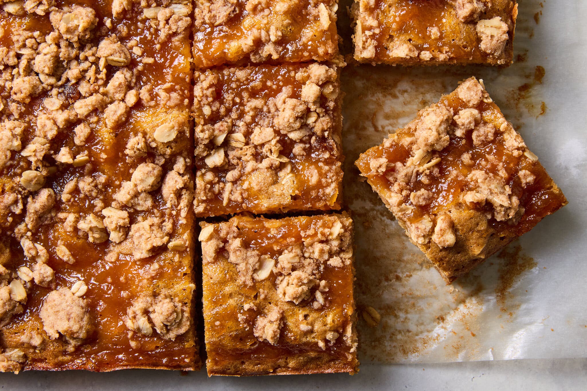 A close-up of a pan of baked squares with a jammy, crumbly textured topping.