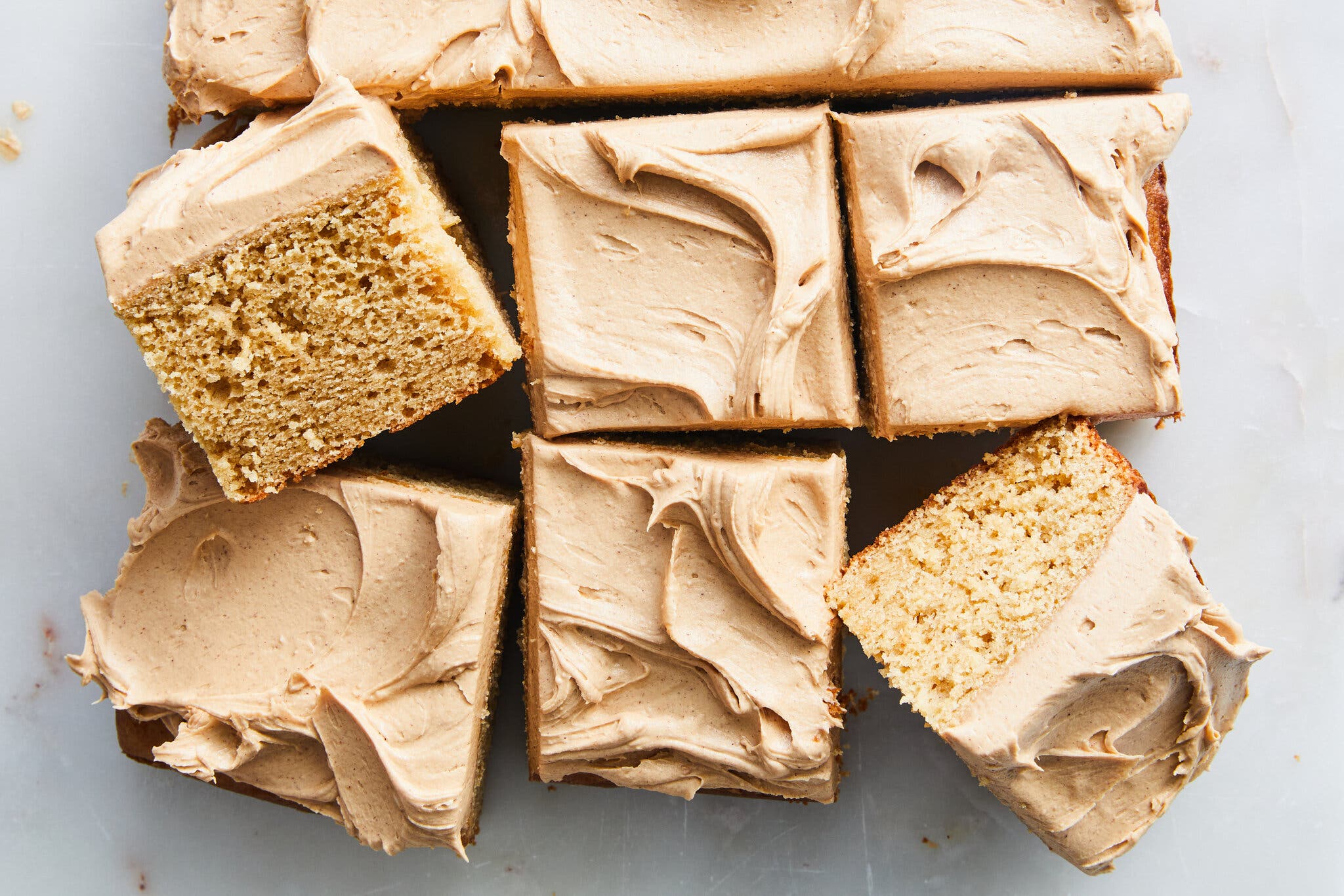 Slices of cake with a thick layer of frosting on a white marble surface.