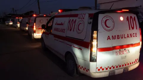 Reuters Red Crescent ambulances lined up behind one another in the dark