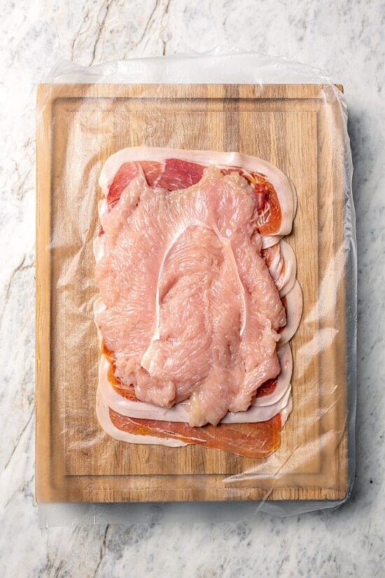 This Prosciutto Wrapped Stuffed Turkey Tenderloin recipe is filled with apples, cheese and kale for a healthy high-protein dinner. Delicious! Turkey tenderloin set over layer of prosciutto.