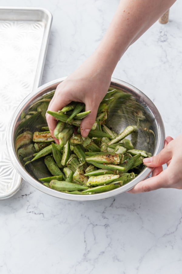 Tossing okra to coat evenly with oil and seasonings.