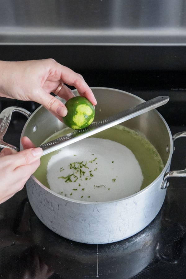 Zesting a lime into saucepan along with sugar and green tomato puree.