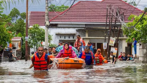 Getty Images A rescue team evacuates women and children in a rubber boat, in West Sumatra, Indonesia