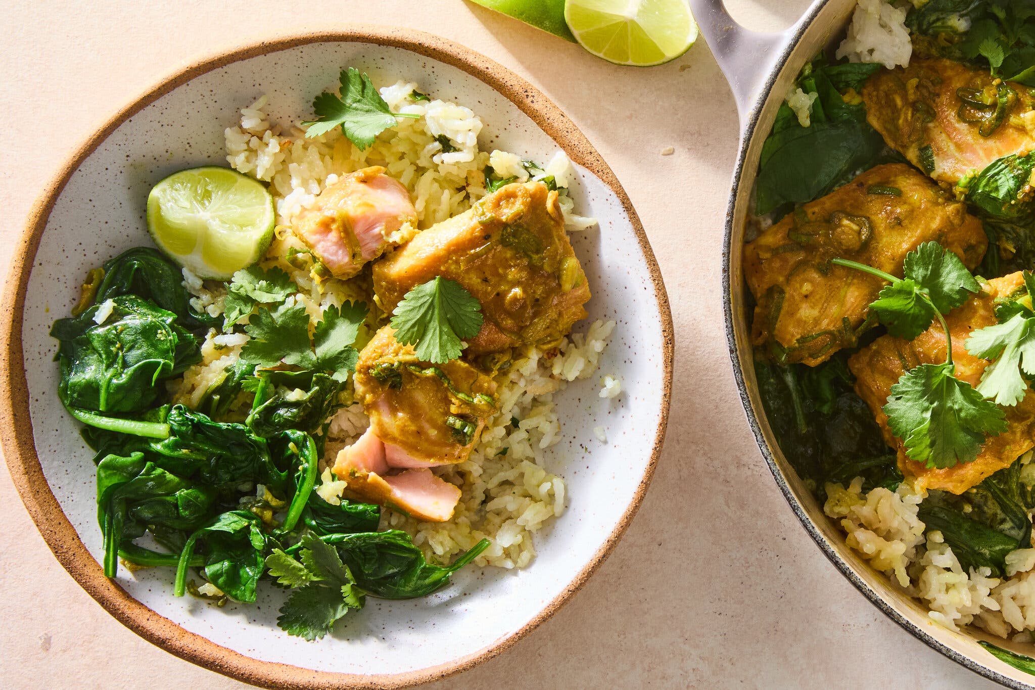 An overhead image of a white bowl filled with rice, salmon and herbs.