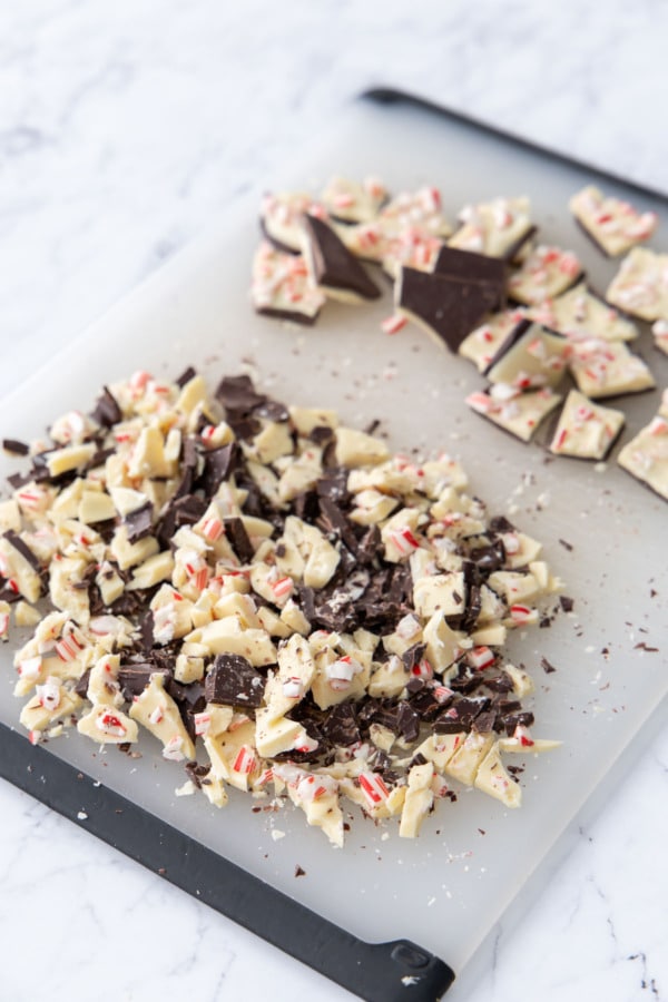 Chopped peppermint bark in two piles, one chip-sized to mix in to the dough, and larger squares for topping.