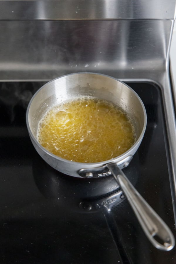 Melted butter bubbling in a small saucepan on an electric stovetop.