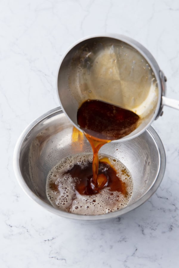 Pouring reduced maple syrup into the mixing bowl with brown butter.